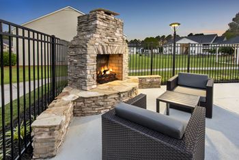 an outdoor patio with a stone fireplace and a table and chairs